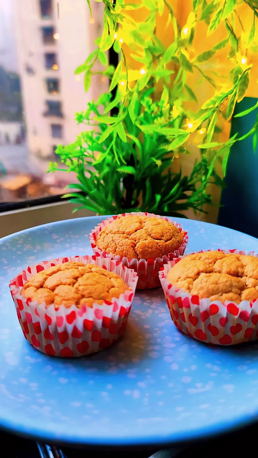 Three cupcakes in heart-print cases on a blue plate