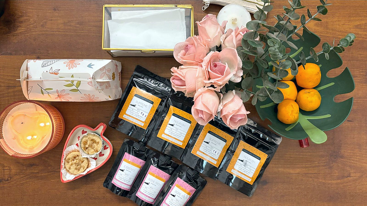 Supreme, Nourish, Essence and Bone Rich pouches on a table with two cupcakes and flowers